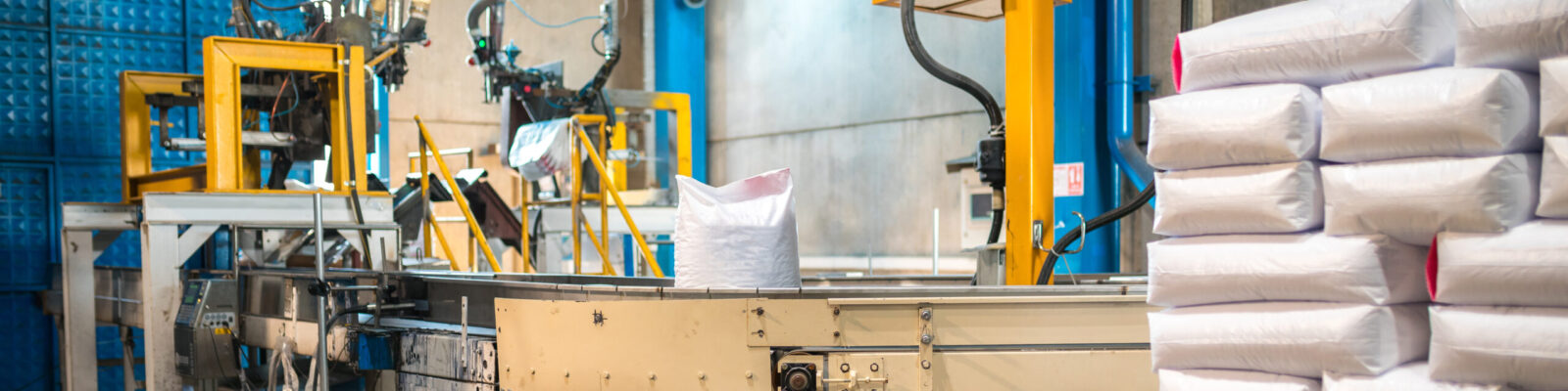 Rows or stacks of white sack bags at large warehouse in modern factory. Packaging on factory machine band or warehouse