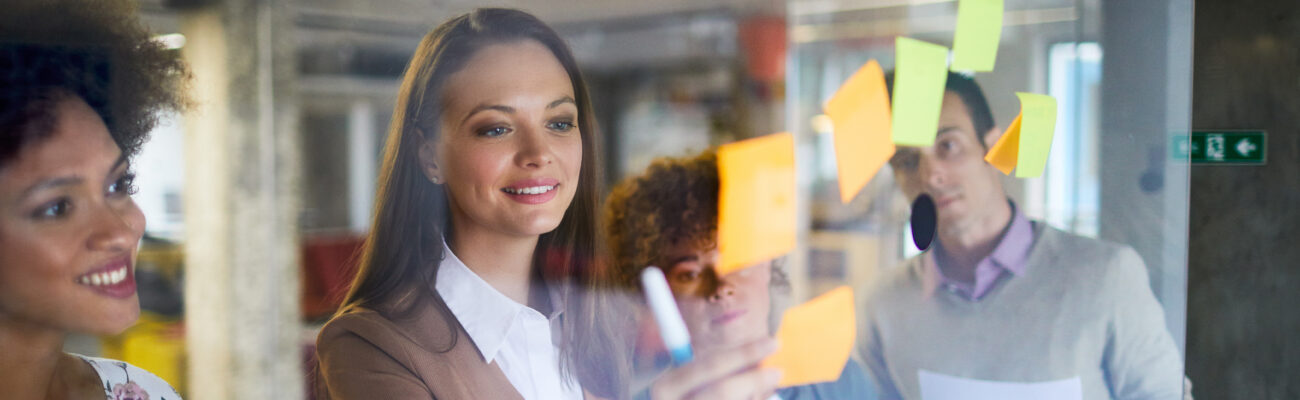 Business people putting sticky notes on a glass board in a modern office