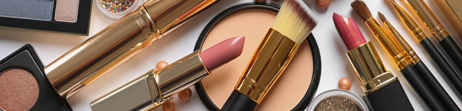 Different luxury makeup products on white background, top view