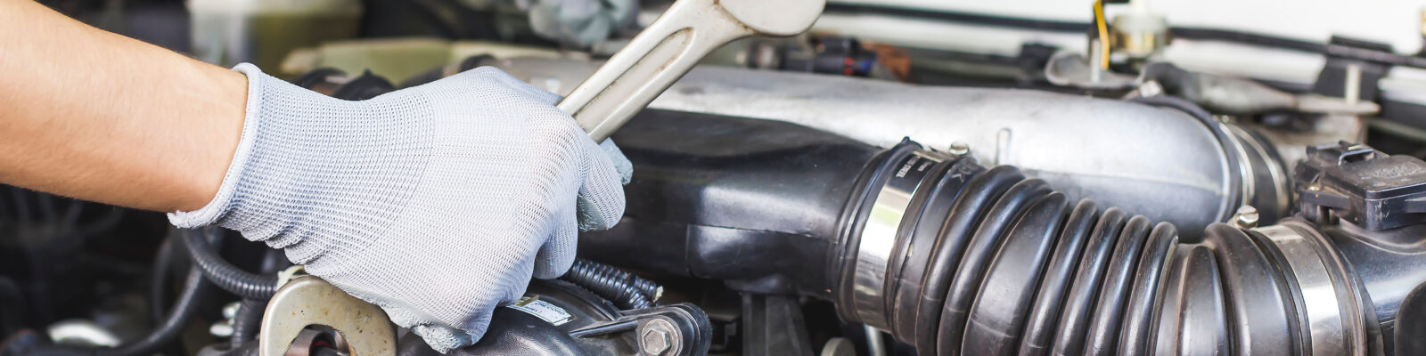 A car mechanic is doing a car repair in a repair shop.