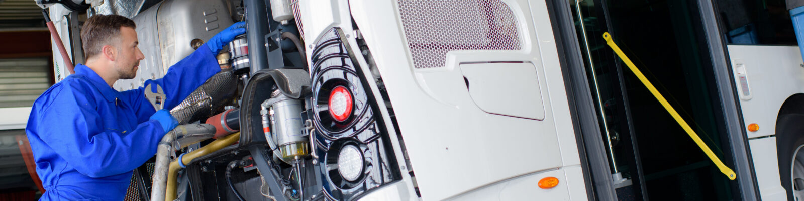 Mechanic working on engine of public transport bus